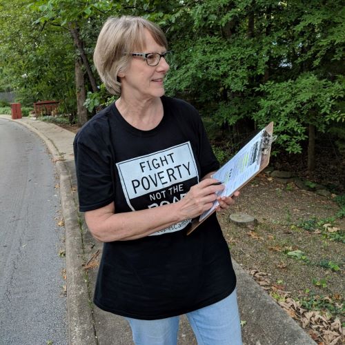 Woman holding clipboard with a Fight Poverty T-shirt